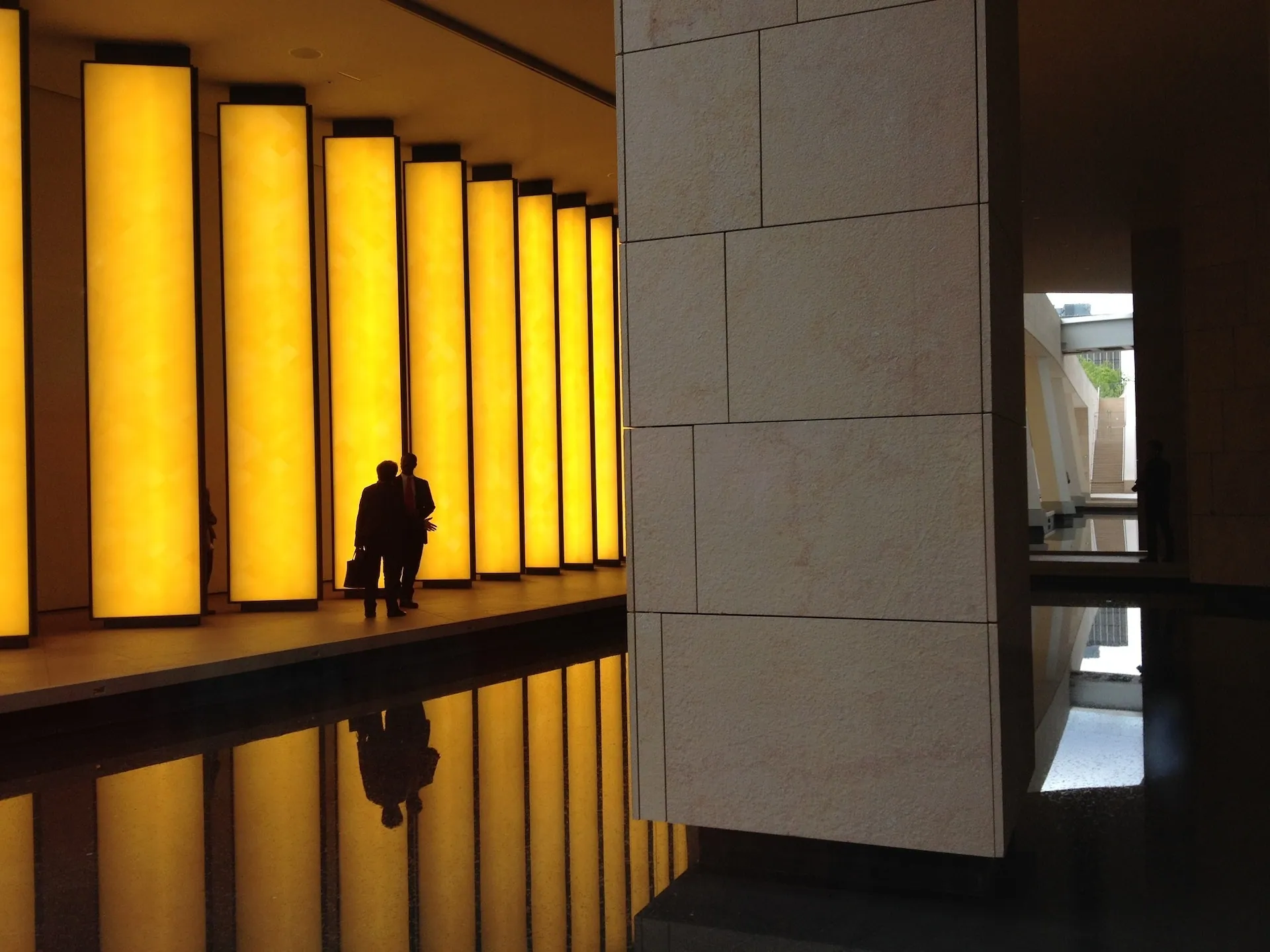 Person silhouetted in a corridor lit by tall amber lights