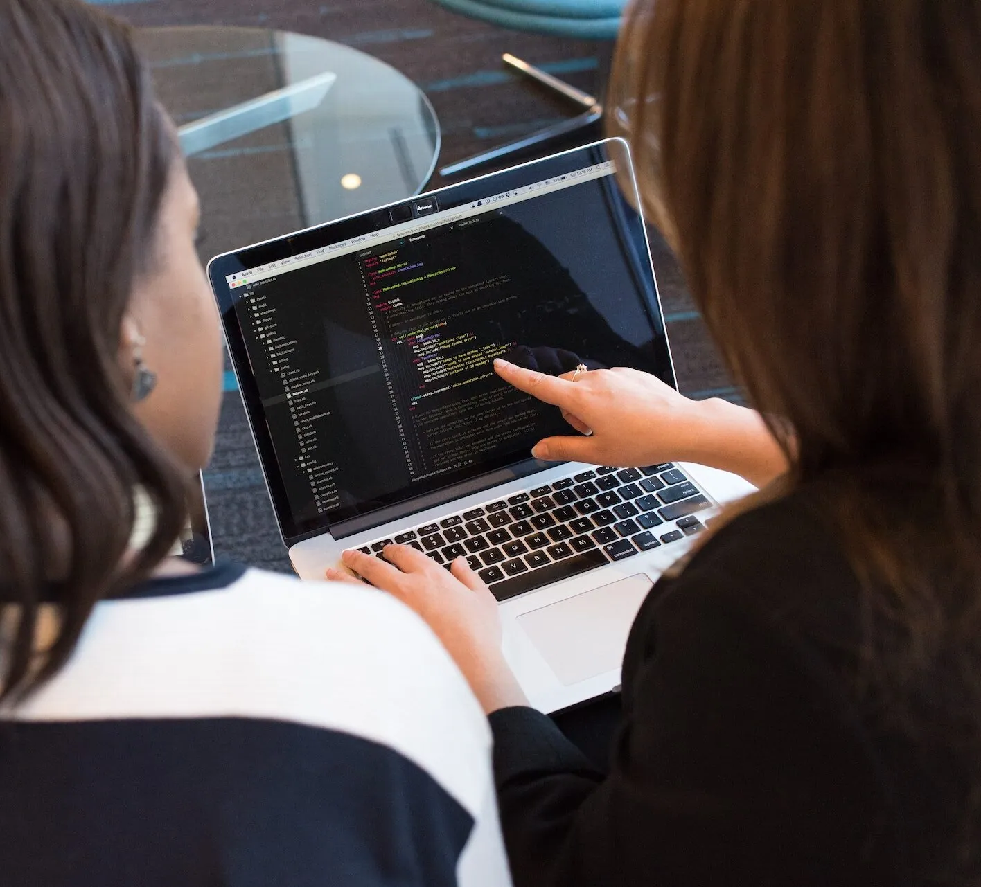 Two people looking at code on a laptop