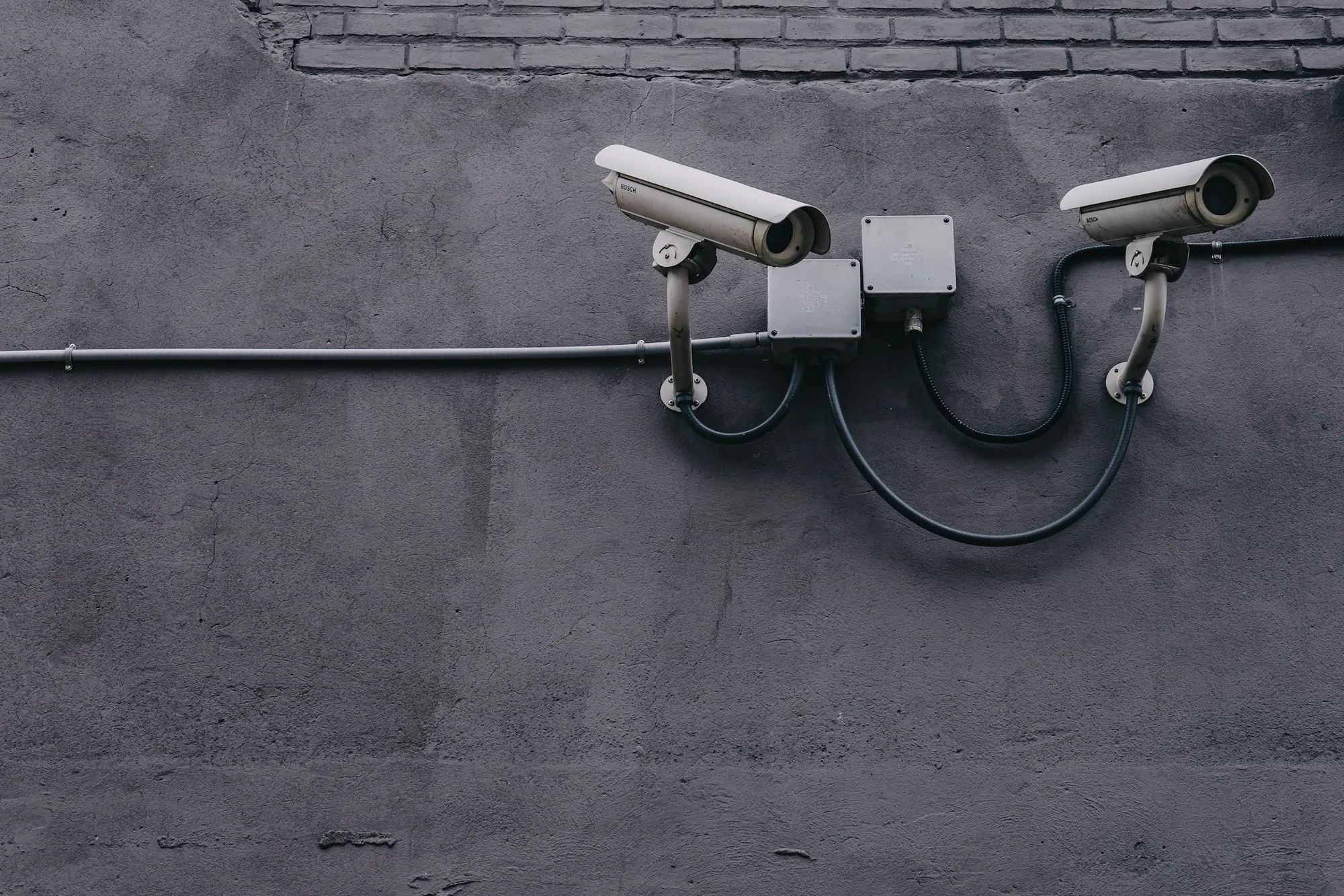 Two CCTV cameras mounted on a grey wall