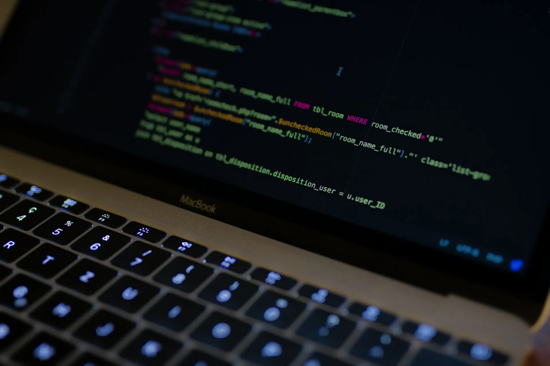 Backlit laptop keyboard and screen showing code